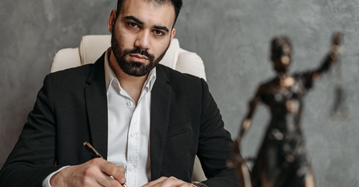 A serious lawyer in a black suit working diligently at his office desk.