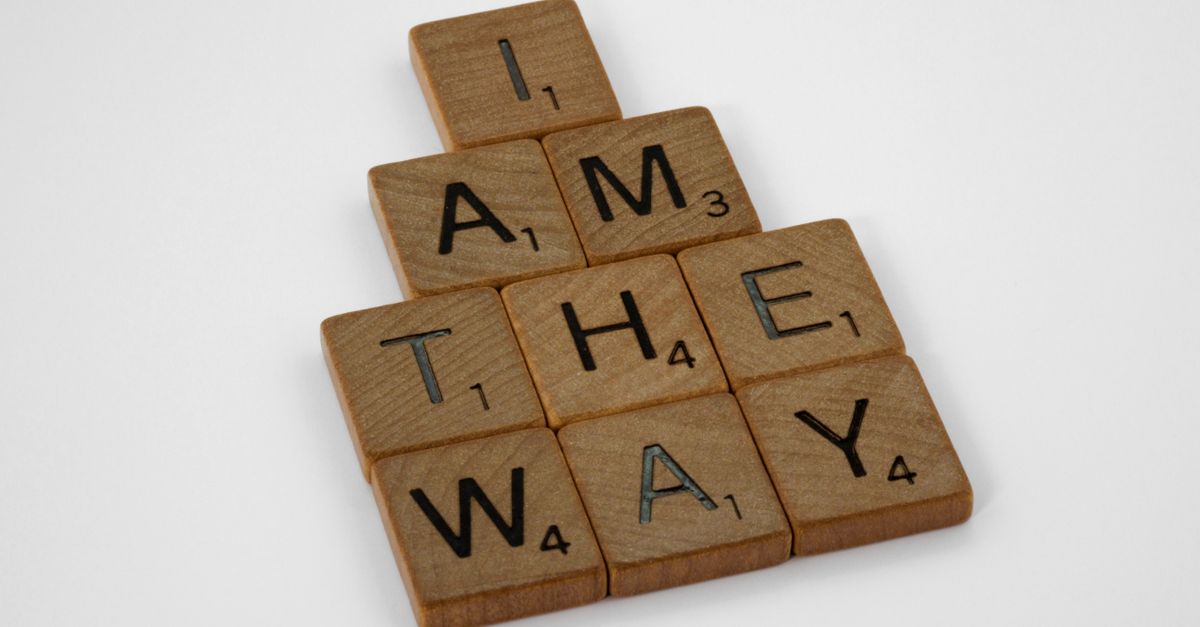 Wooden Scrabble tiles spell 'I Am the Way' on a white surface, offering a simple message in a minimalist style.