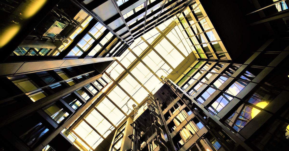 Dynamic low-angle view of a modern building's glass ceiling showcasing reflections and light.