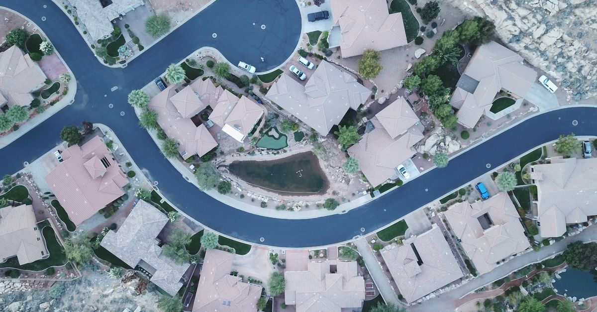 Drone aerial photo of a suburban neighborhood street layout with houses and greenery.