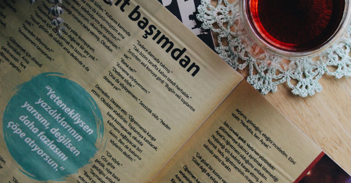 A relaxing moment with a cup of Turkish tea and an open magazine on a wooden table.
