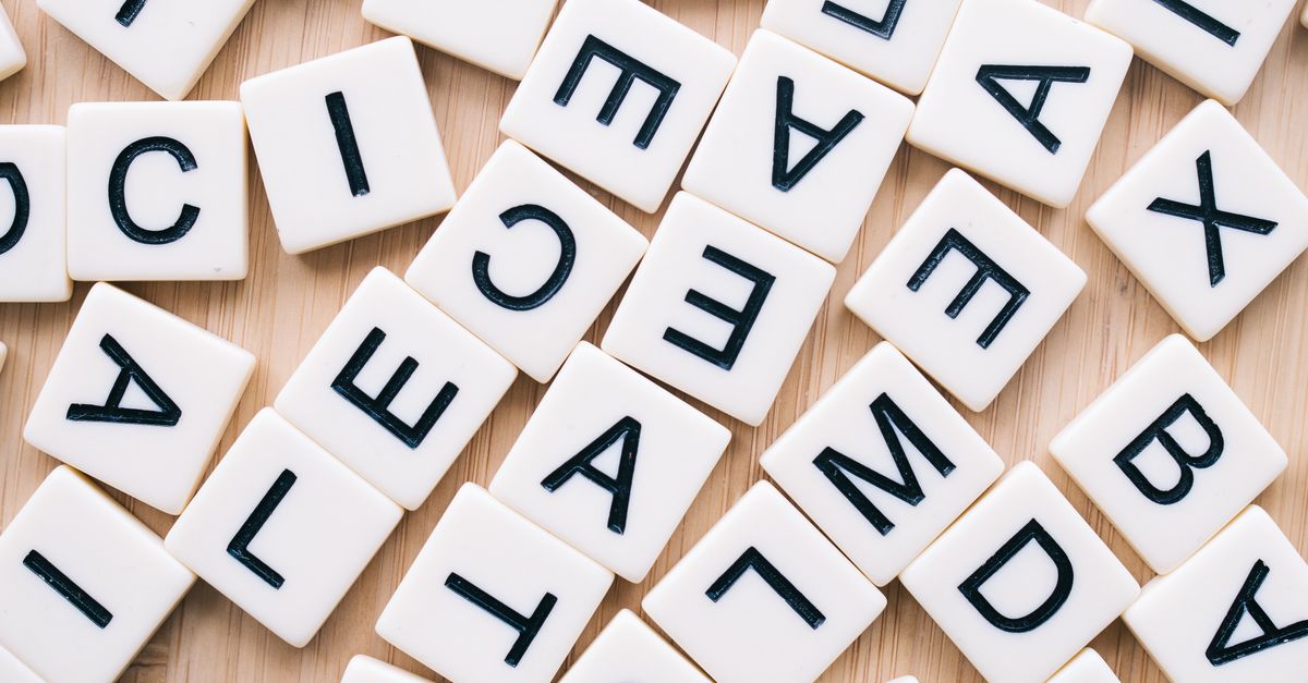 A close-up of scattered letter tiles on a wooden surface, captured from above.