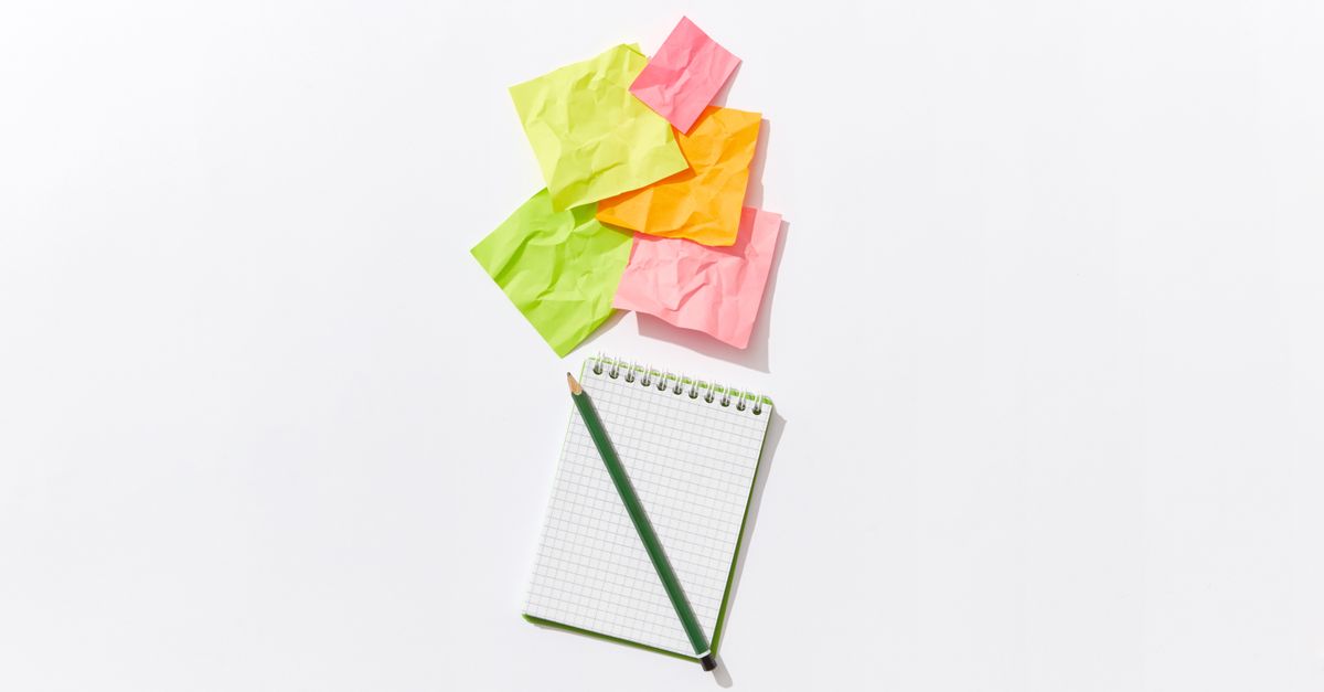 Colorful flat lay of crumpled sticky notes with a notepad and pencil on white background.